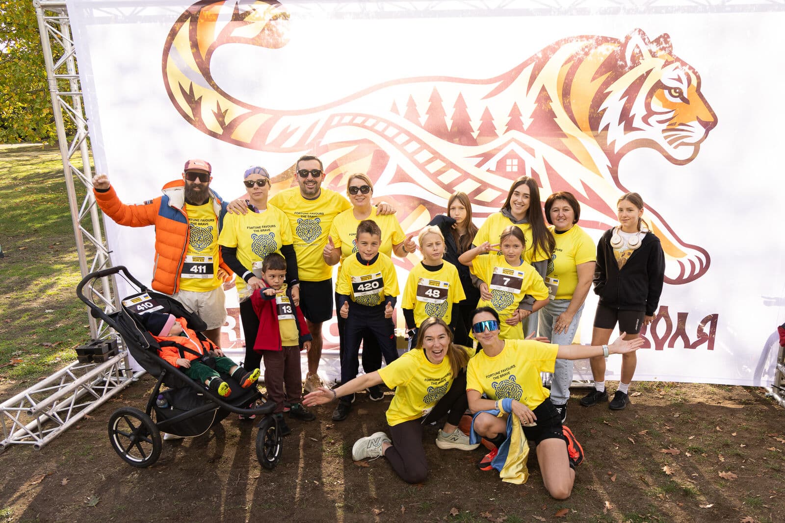 A team posing with a pram in front of the tiger banner