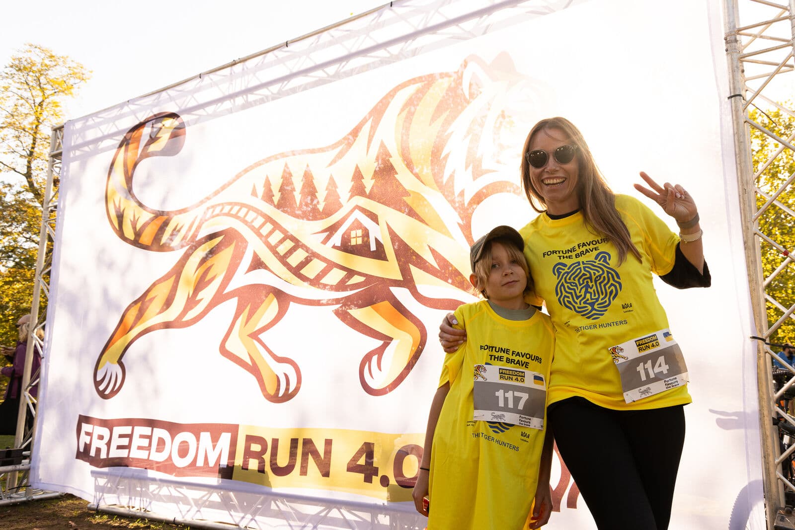 A mother and child with their race numbers by the tiger banner