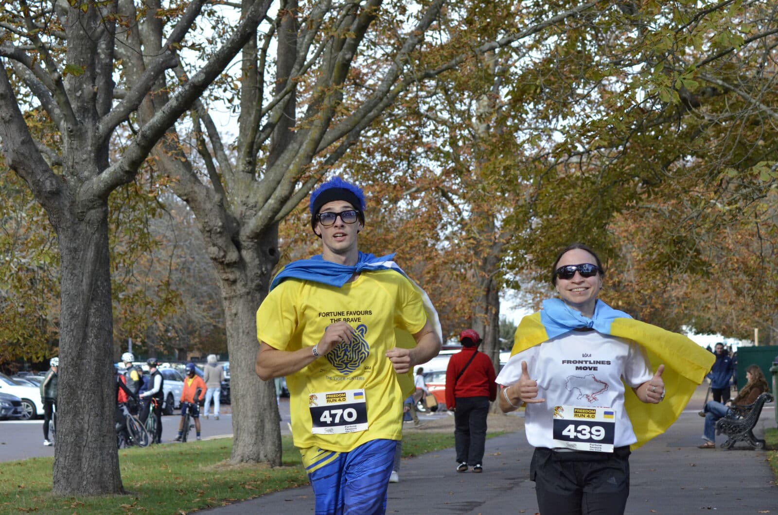 Two runners wearing Ukrainian flags as capes heading for the finish