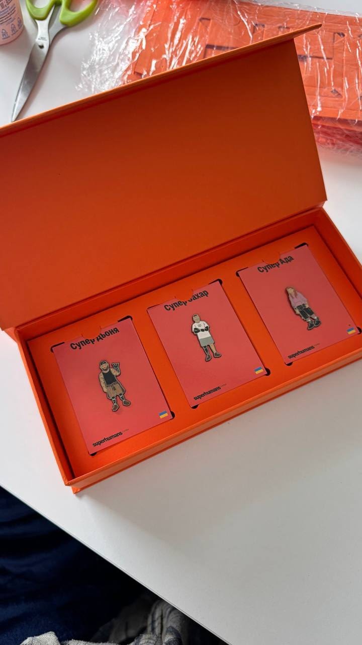 The open Superhumans gift box with three pins