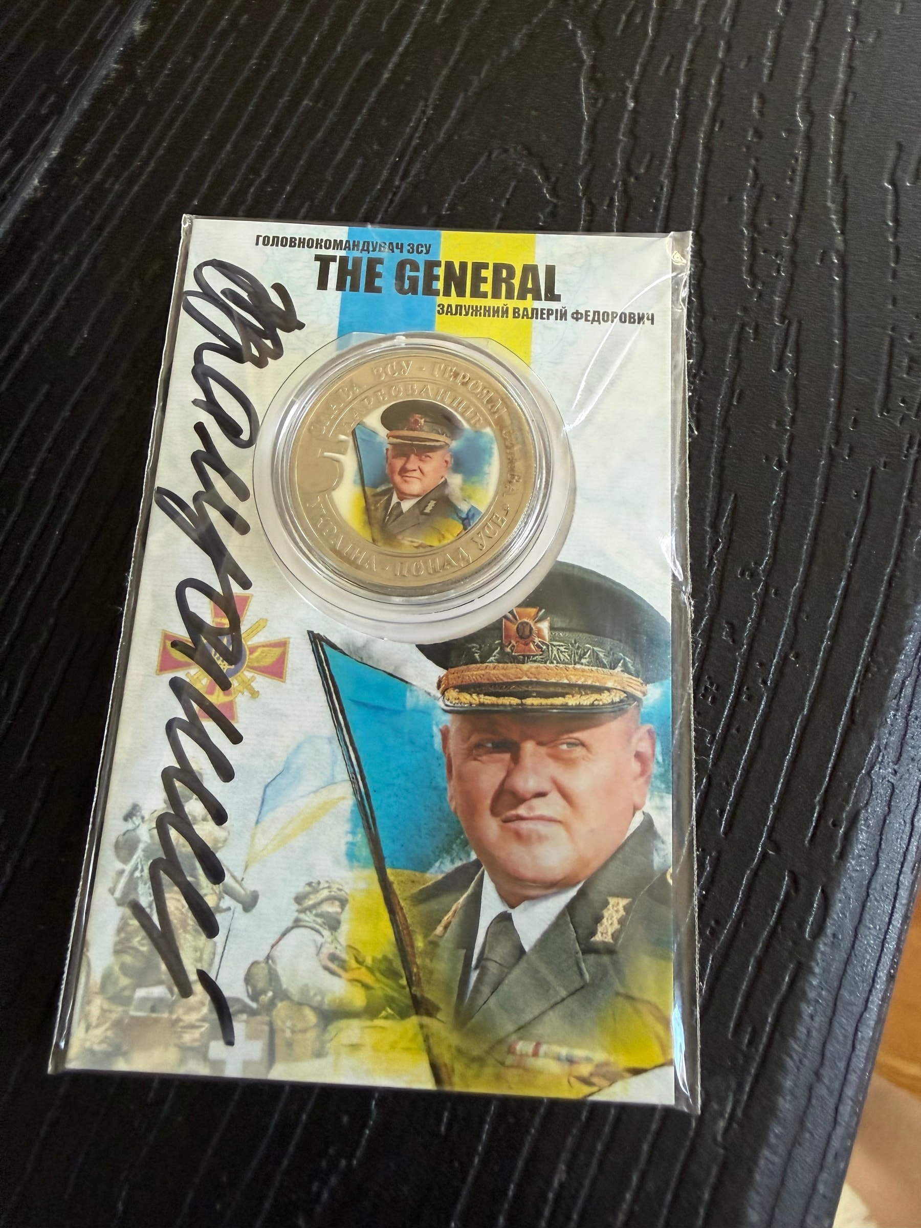 The signed coin in its card, front